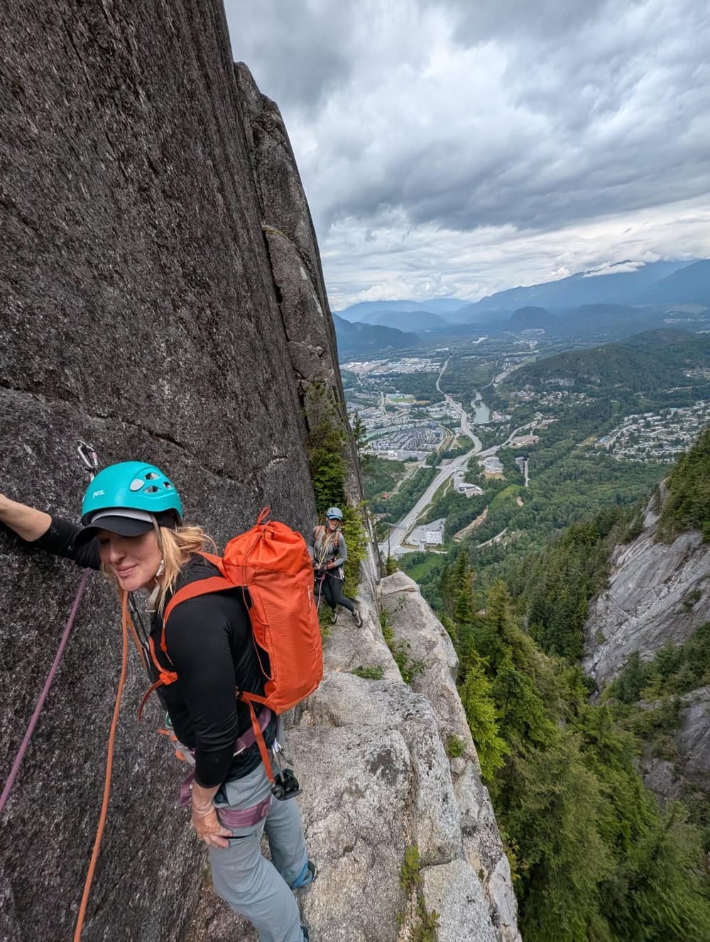Kat Heldman climbing a cliff with a valley below