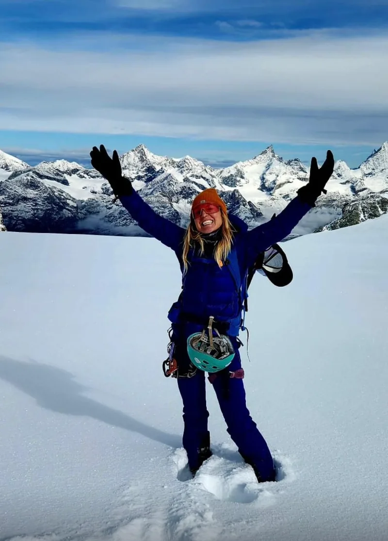 Kat Heldman celebrating on a snowy summit